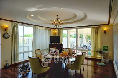 Spacious living room with elegant chandelier and large windows offering natural light and garden view.