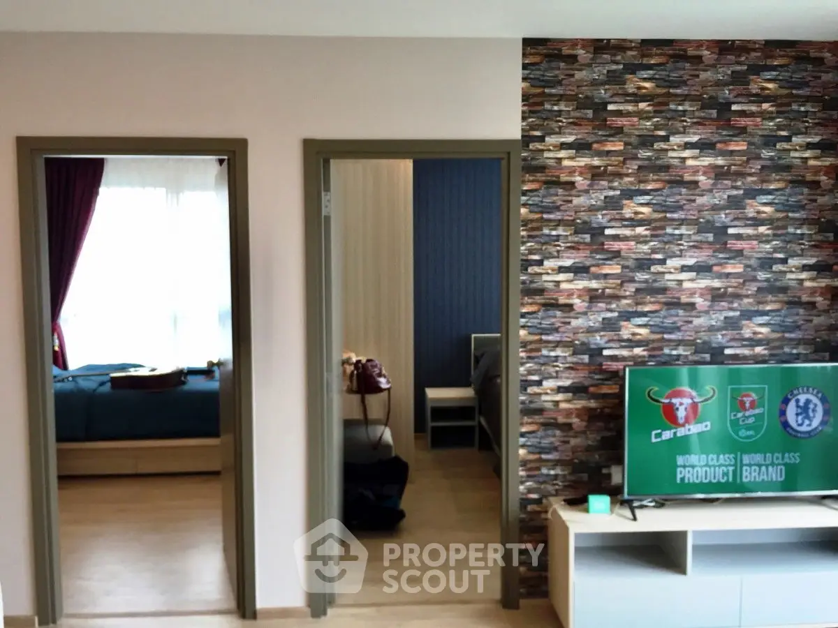 Modern apartment interior with stylish living room and bedroom view, featuring a TV and decorative wall.