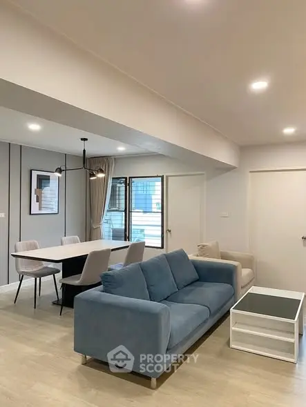 Modern living room with blue sofa and dining area, bright and spacious design.