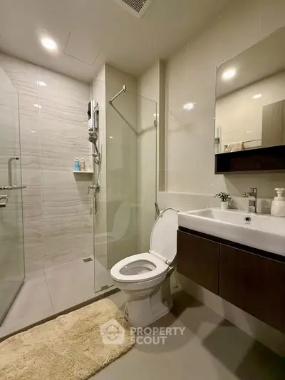 Modern bathroom with glass shower and sleek vanity in contemporary apartment.
