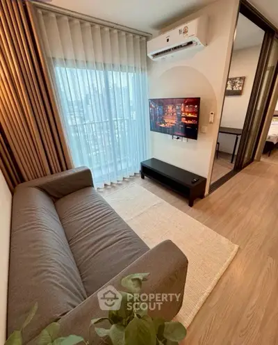 Modern living room with city view, featuring a cozy sofa and wall-mounted TV.