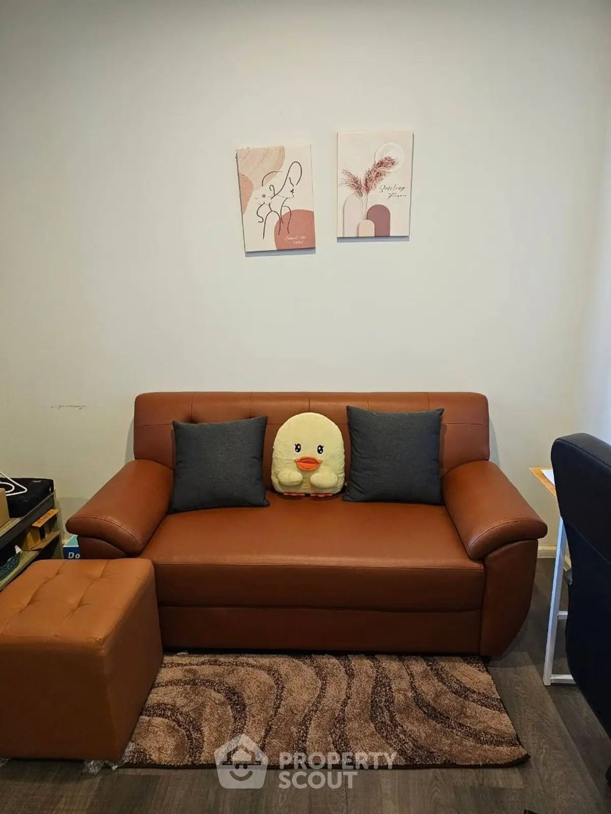 Cozy living room with brown leather sofa and cute duck pillow, perfect for relaxation.