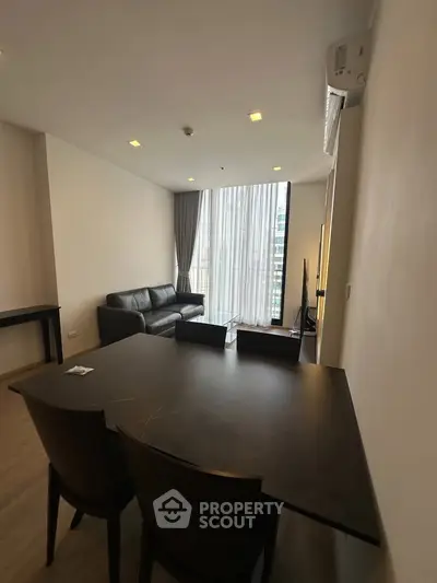 Modern living room with high ceilings and large windows in a stylish apartment.