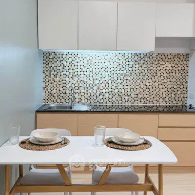 Modern kitchen with mosaic backsplash and dining setup in a stylish apartment.