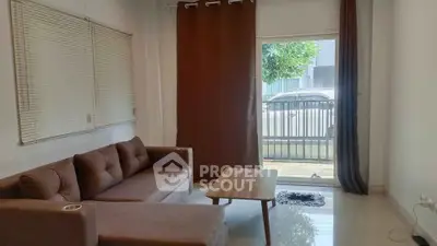 Cozy living room with brown sofa and curtains, overlooking a small balcony.
