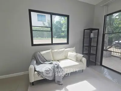 Bright living room with cozy white sofa and large windows overlooking greenery.