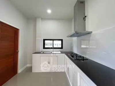 Modern kitchen with sleek black countertops and gas stove, featuring a minimalist design and ample natural light.