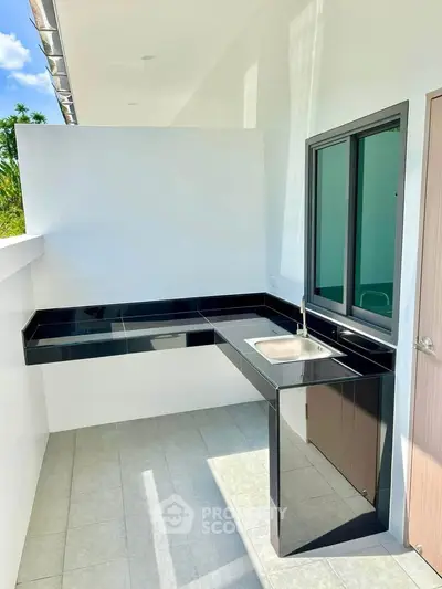 Modern outdoor kitchen with sleek black countertops and stainless steel sink