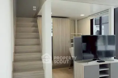 Modern compact living space with staircase and TV, showcasing efficient design.