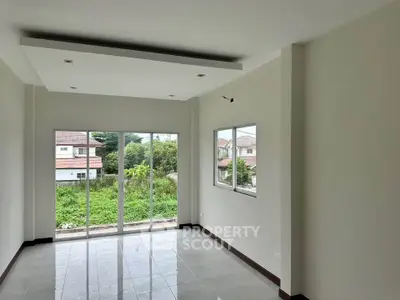Spacious living room with large windows offering lush garden views in modern home.
