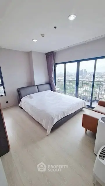 Spacious bedroom with large windows offering stunning city views