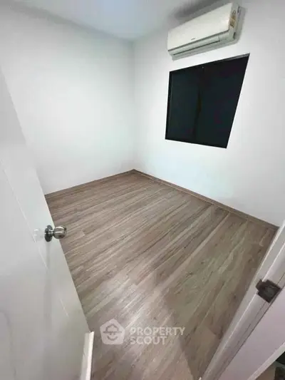 Spacious empty room with wooden flooring and air conditioning, perfect for customization.