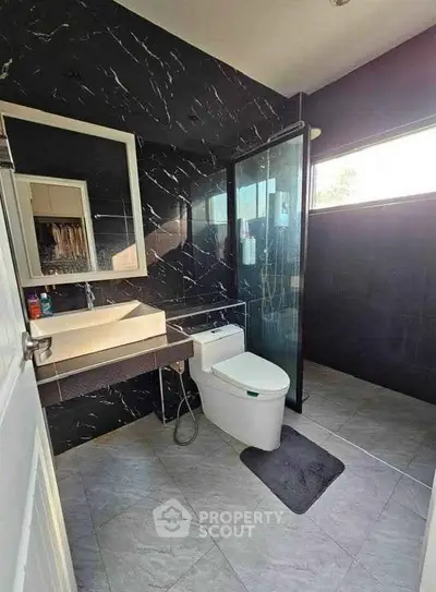 Modern bathroom with sleek black tiles and glass shower enclosure
