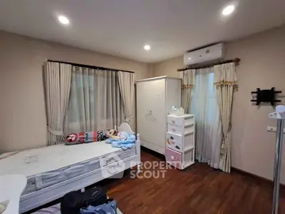 Cozy bedroom with wooden flooring, elegant curtains, and ample storage space.