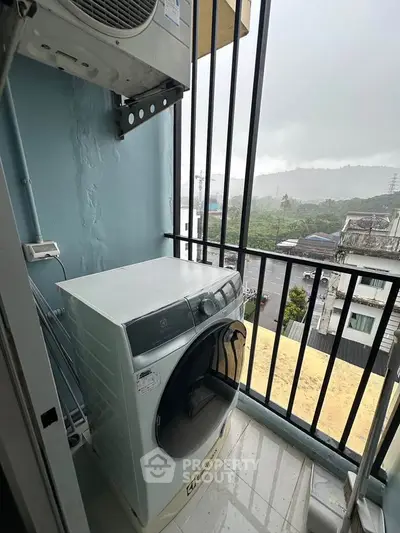 Compact balcony with washing machine and scenic view of surrounding landscape.
