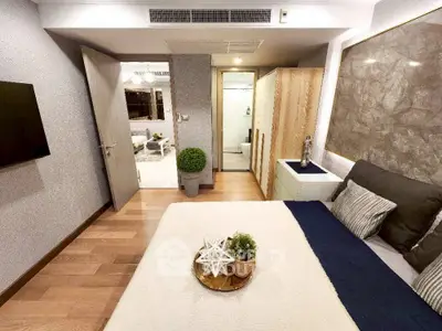 Modern bedroom with stylish decor and wooden flooring, leading to a spacious living area.