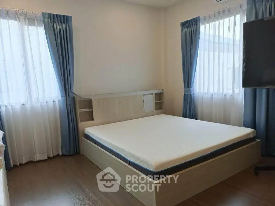 Spacious bedroom with large windows and modern furnishings, perfect for a cozy and comfortable living experience.
