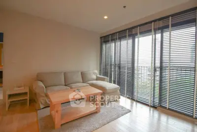 Spacious living room with cozy sofa and large windows offering natural light and garden view.