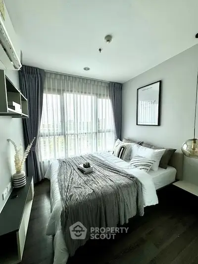 Modern bedroom with large window, stylish decor, and cozy bedding in a contemporary apartment.