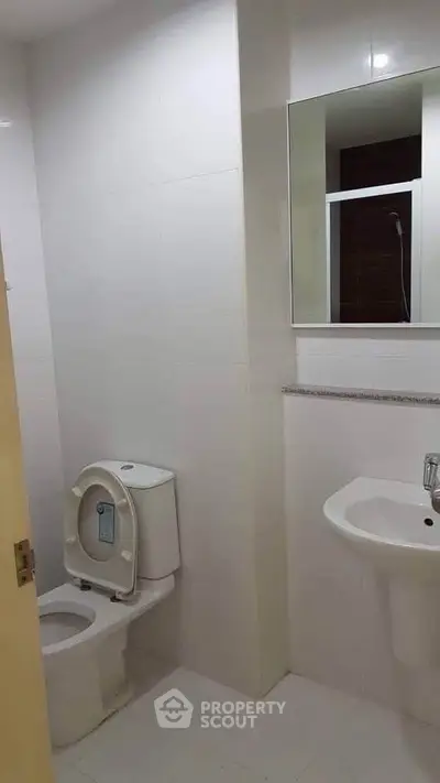 Modern bathroom with sleek white fixtures and a large mirror, perfect for contemporary living.