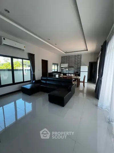 Spacious modern living room with sleek black furniture and large windows for natural light.