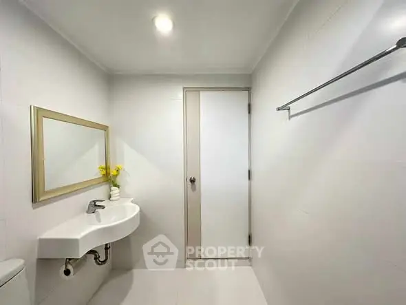 Minimalist bathroom with white walls, modern sink, and decorative mirror.