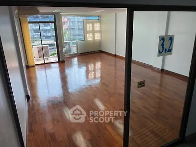 Spacious empty room with polished wooden floors and large windows offering ample natural light.
