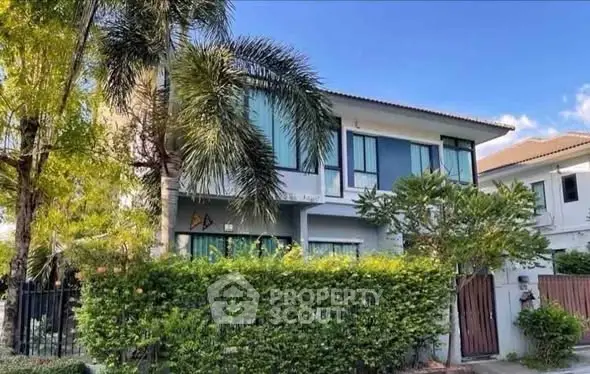 Charming two-story house with lush greenery and modern design in a serene neighborhood.