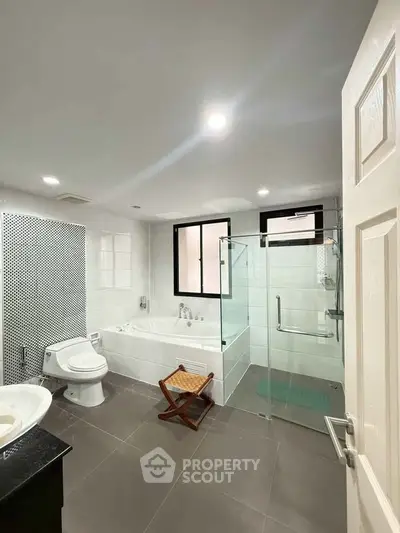 Spacious modern bathroom with bathtub and glass shower enclosure