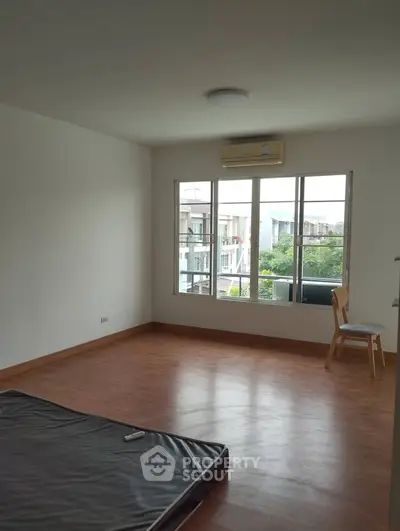 Spacious unfurnished room with large window and air conditioning, perfect for customization.