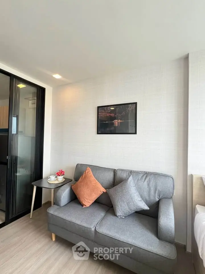 Modern living room with stylish gray sofa and decorative pillows, featuring a sleek side table and wall art.