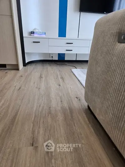 Modern living room with stylish wooden flooring and sleek white furniture.