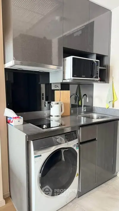 Modern compact kitchen with sleek cabinets, built-in appliances, and washing machine in stylish apartment.