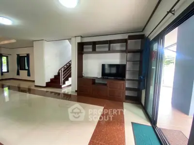 Spacious living room with modern TV unit and sliding glass doors opening to balcony.