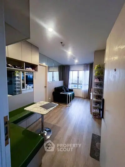 Modern living room with stylish decor and ample natural light, featuring a cozy seating area and sleek storage solutions.