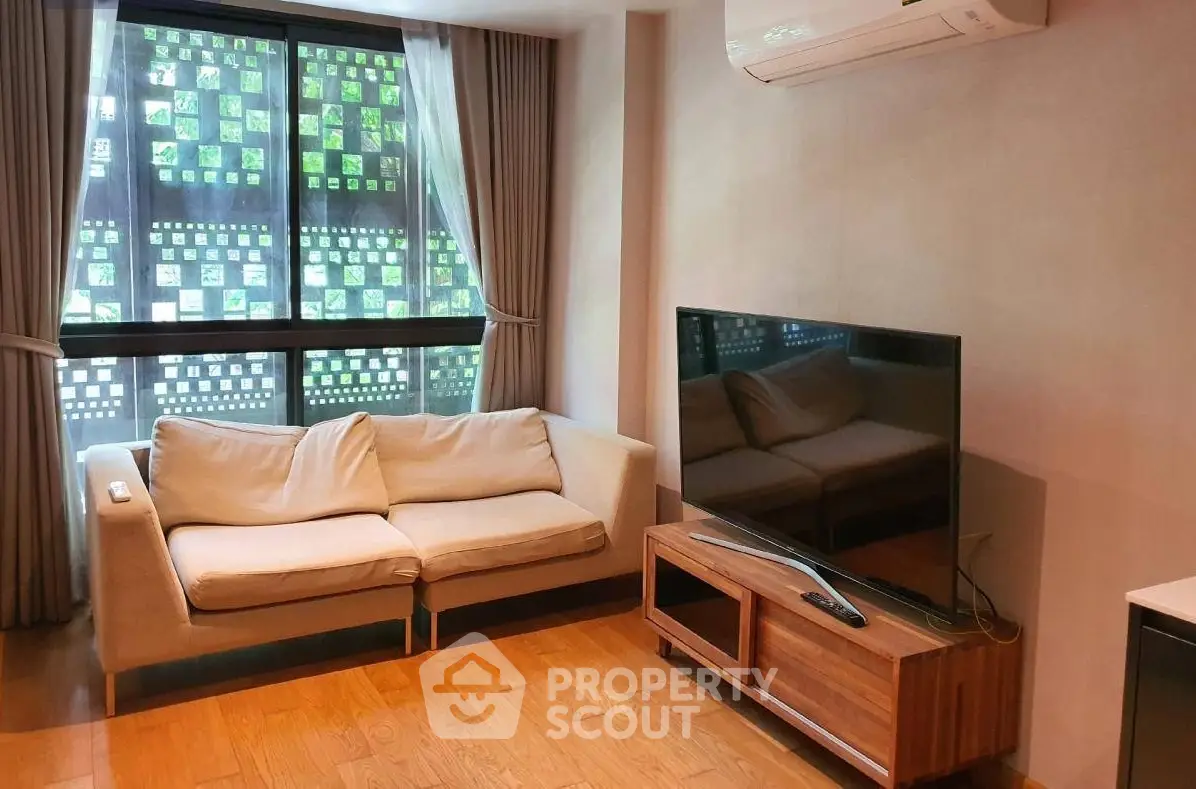 Modern living room with cozy sofa, large TV, and air conditioning, featuring stylish window design.