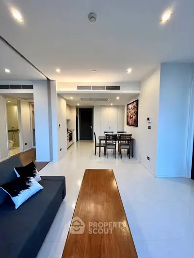 Modern open-plan living room with sleek kitchen and dining area, featuring contemporary decor and ample natural light.