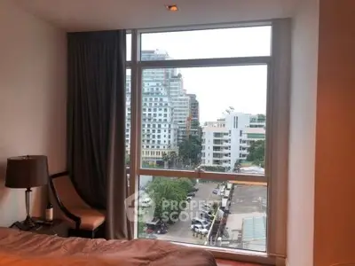 Spacious bedroom with large window offering stunning city view in modern apartment.