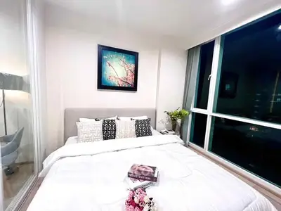 Modern bedroom with large window and stylish decor in a high-rise apartment.