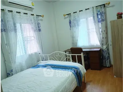 Cozy bedroom with natural light, featuring a bed, desk, and elegant curtains for a serene living space.