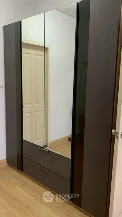 Modern bedroom with sleek mirrored wardrobe and wooden flooring