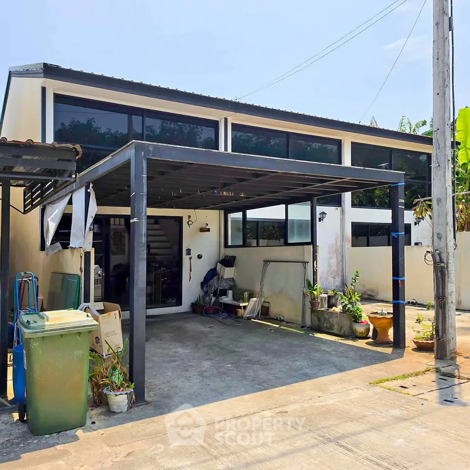 Modern two-story house with large windows and covered carport in a suburban setting.