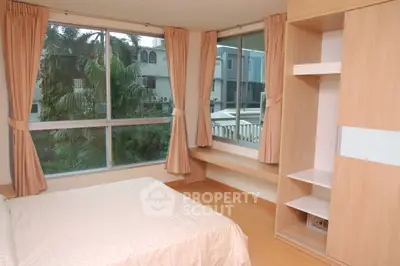 Spacious bedroom with large windows and built-in wardrobe overlooking lush greenery.
