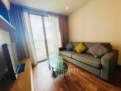 Cozy living room with modern sofa and glass coffee table, featuring a large window with city view.