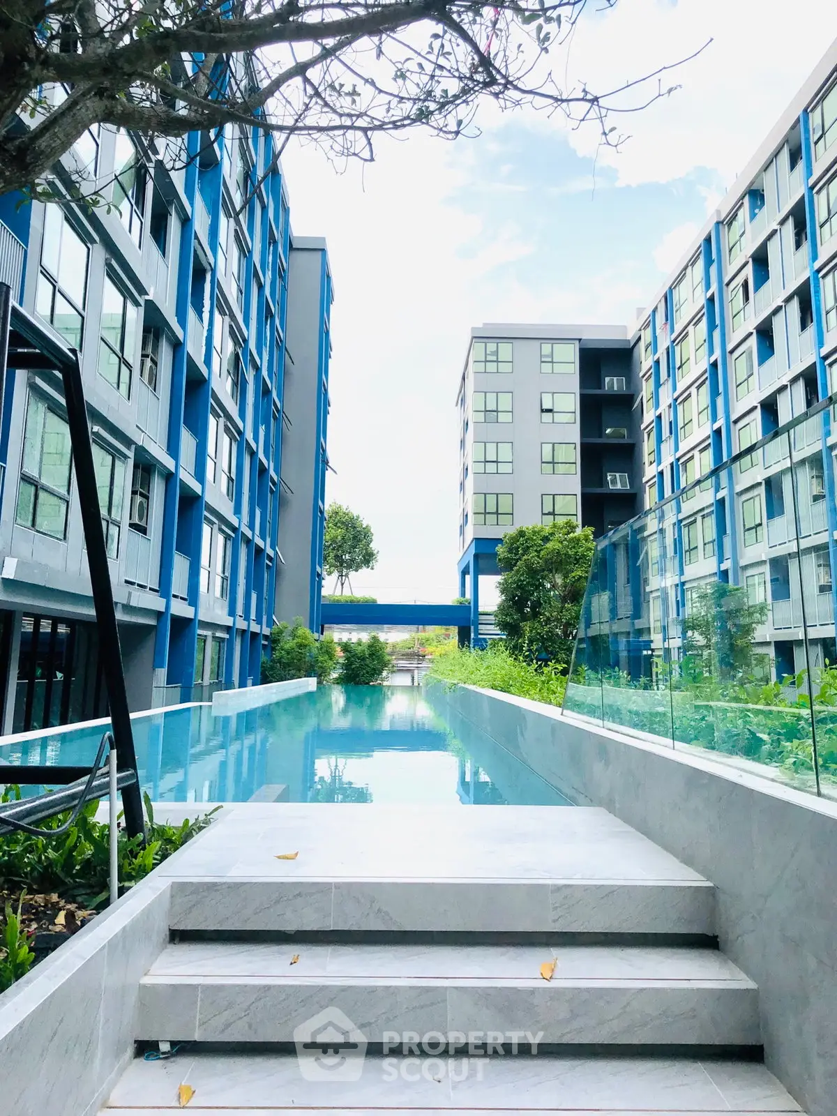 Modern apartment complex with sleek pool and lush greenery, offering a luxurious urban living experience.
