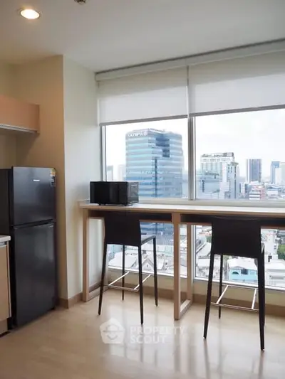 Modern kitchen with city view, featuring sleek appliances and a breakfast bar with stools.