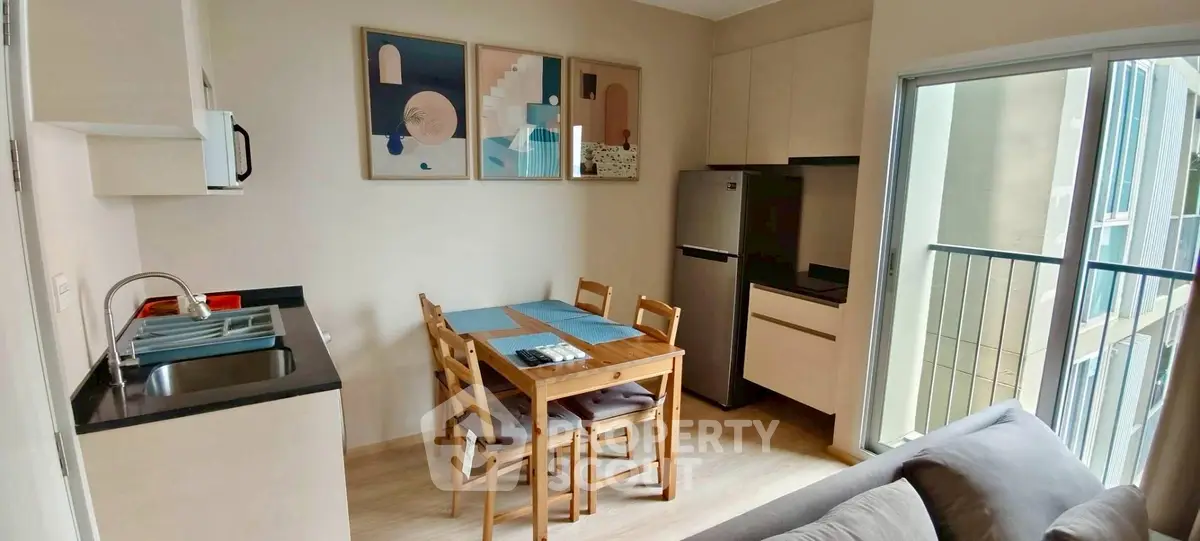 Modern kitchen with dining area and balcony access in a cozy apartment.