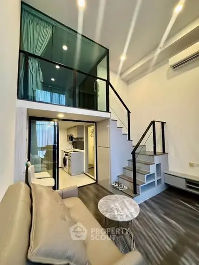Modern loft apartment with mezzanine, stylish living area, and sleek kitchen featuring washing machine.