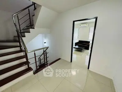 Modern interior with staircase and living room view, sleek design and bright lighting.