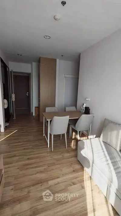 Modern living room with wooden flooring and cozy dining area in a stylish apartment.